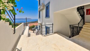 Una escalera conduce a un balcón con vistas a un pueblo costero y una vista despejada del mar.