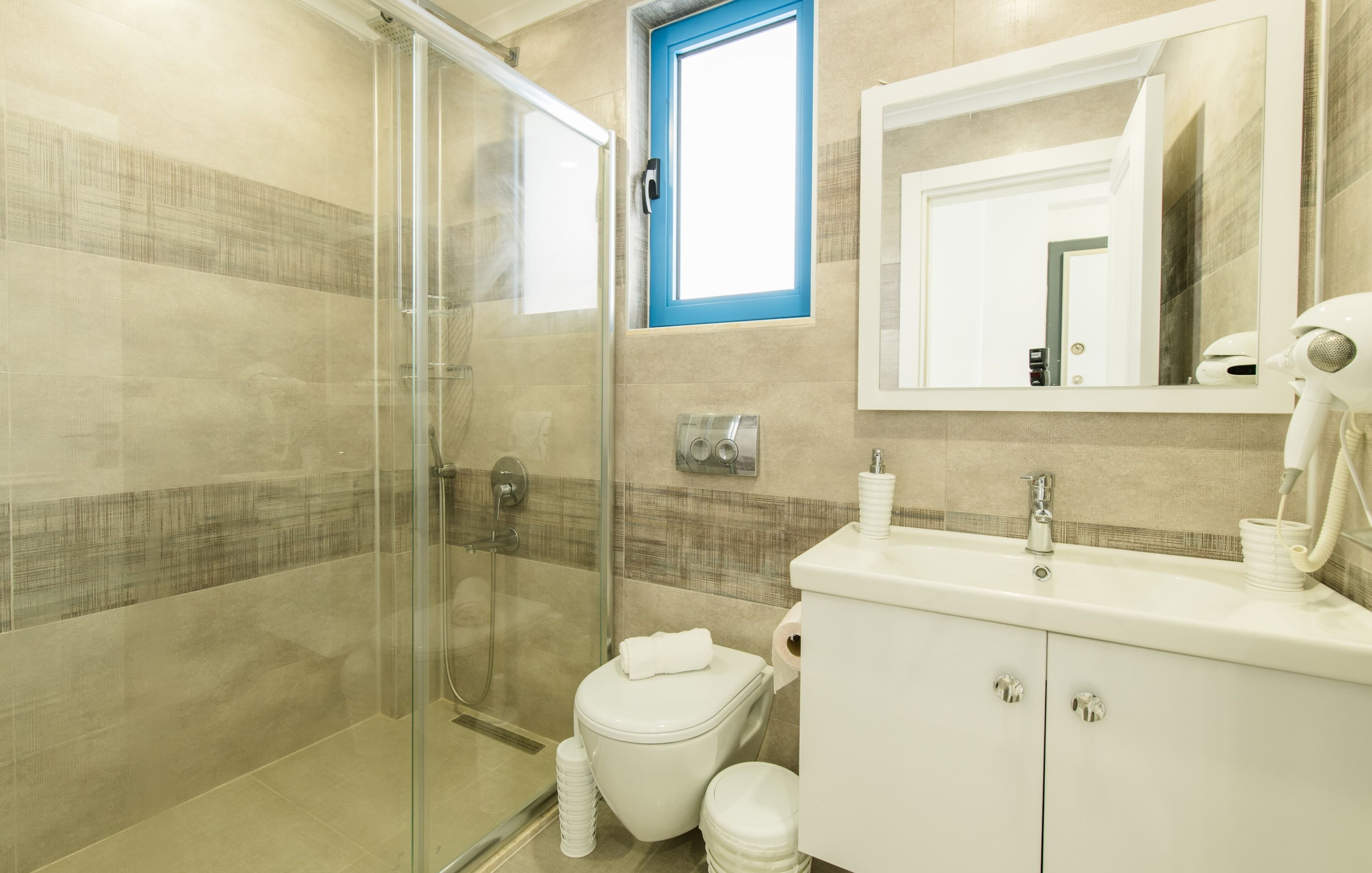 A modern bathroom with a glass shower enclosure, a white toilet, and a vanity with a mirror.