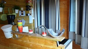 Une cuisine rustique aménagée dans une cabane en bois, avec un plan de travail en bois, un évier et divers ustensiles de cuisine.