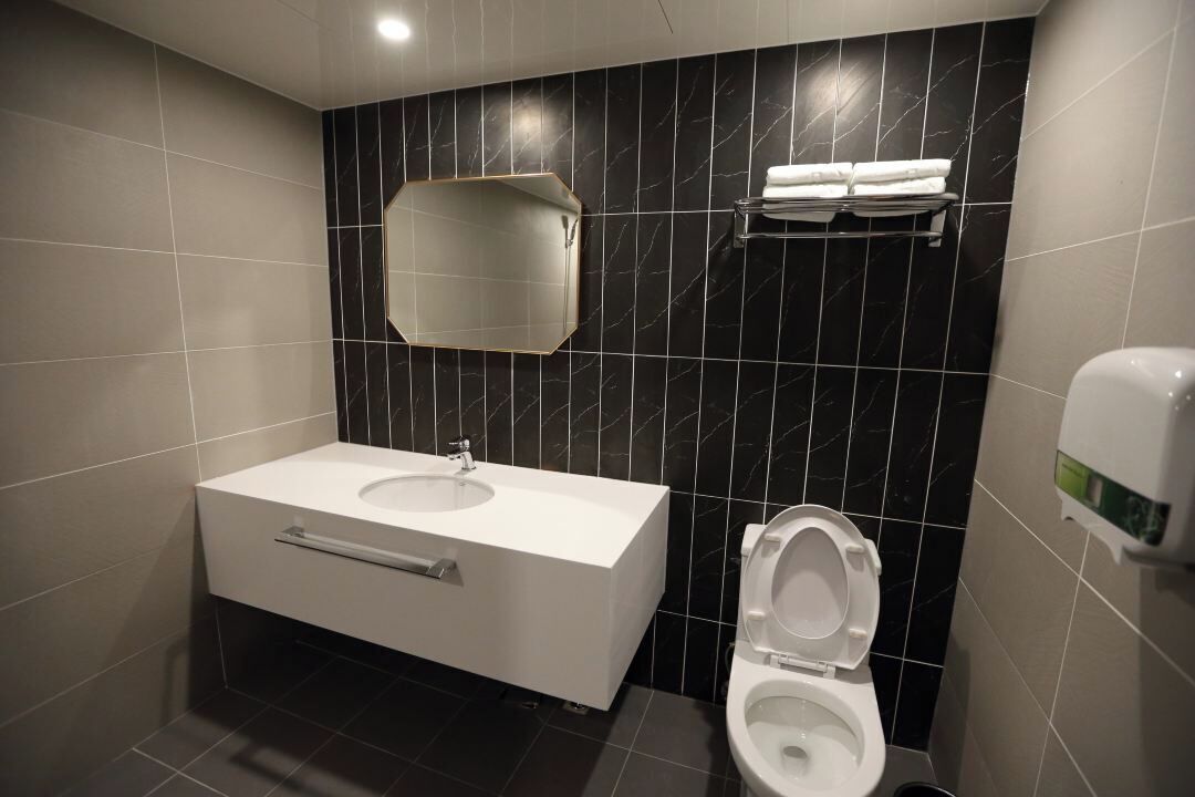 Un baño moderno con un lavamanos blanco, un inodoro y un perchero para toallas.