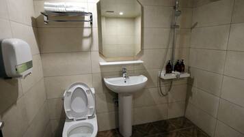 Un baño con inodoro, lavamanos, espejo, toallero y ducha.