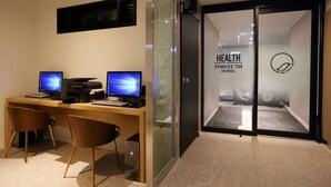 A hotel reception area with a desk, two monitors, and a glass door leading to a fitness room. - Forest 701 Hotel (Daegu)