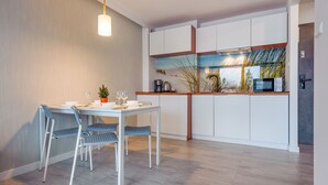 A modern kitchen with white cabinets, a wooden countertop, and a view of a beach through a window. - Apartamenty Sun & Snow Sanatoryjna (Wladyslawowo)