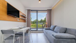 A modern room with a dining area, a sofa, and a balcony with a view. - Apartamenty Sun & Snow Sanatoryjna (Wladyslawowo)