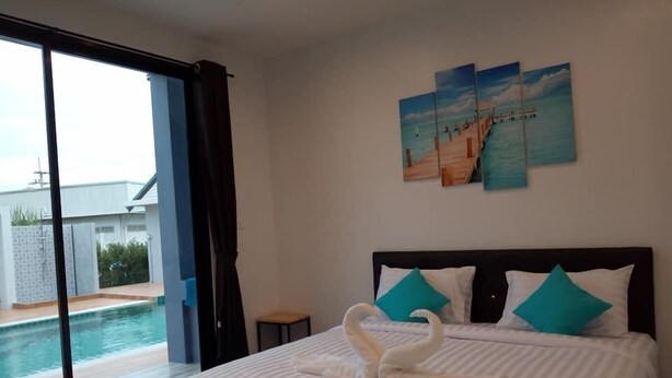 A bedroom with a bed, a view of a swimming pool, and a painting on the wall. - The Phu Resort (Pranburi)
