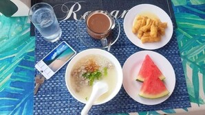 A table with a meal consisting of soup, fried items, and watermelon slices, along with a glass of water and a cup of coffee. - The Phu Resort (Pranburi)