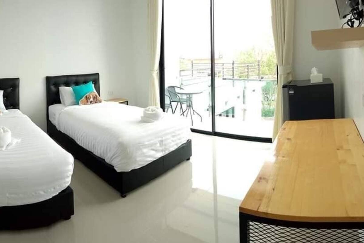 Quarto de hotel com duas camas, uma mesa de madeira e vista para a varanda.