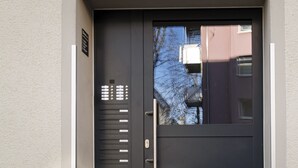 A modern black door with a metal handle and a small window. - Limehome Augsburg Pilgerhausstraße (Augsburg)