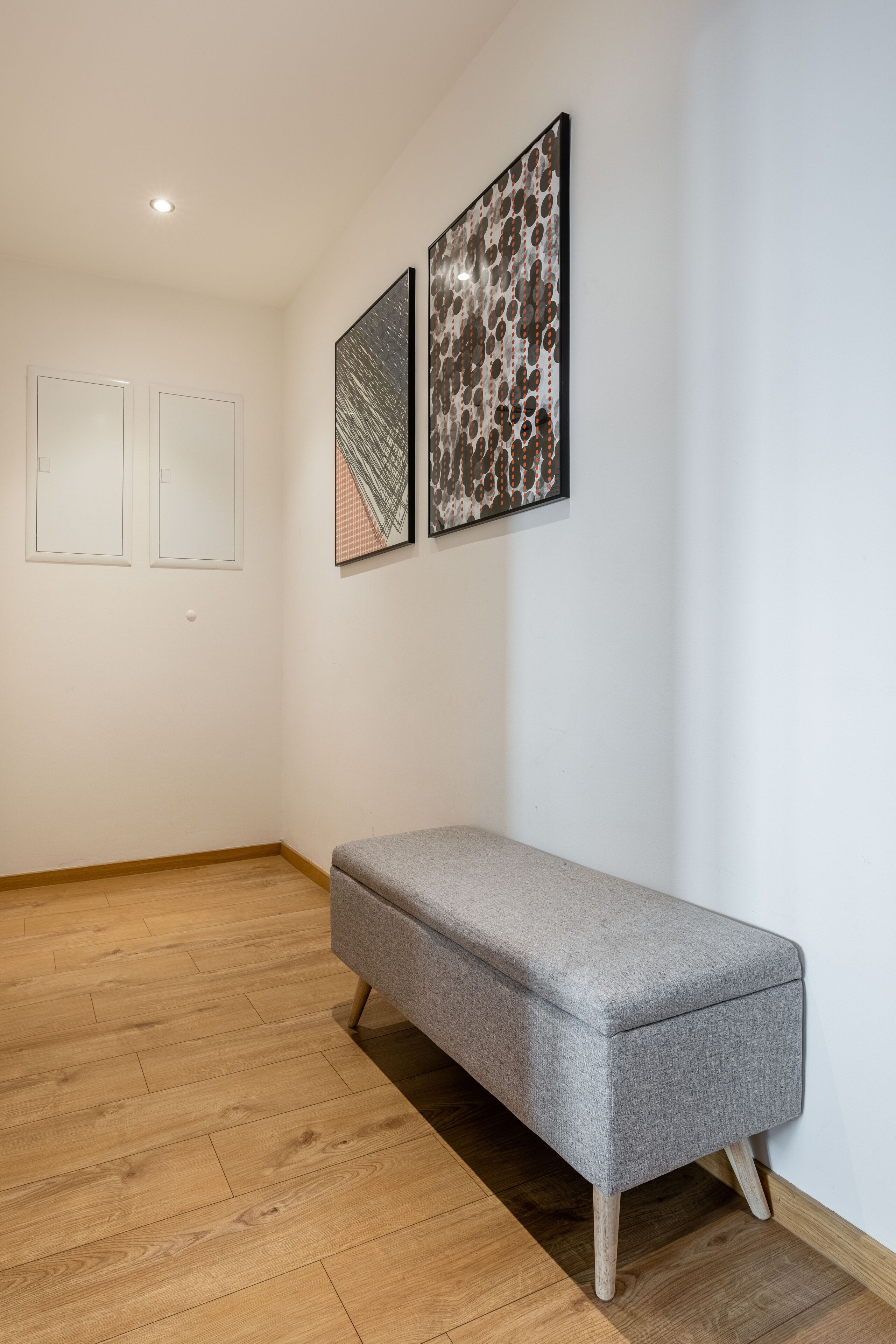 Ein stilvolles Zimmer mit einer Sitzbank, Holzboden und zwei gerahmten Kunstwerken an der Wand.