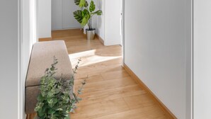 A hallway with wooden flooring, white walls, and a potted plant. - Limehome Augsburg Pilgerhausstraße (Augsburg)