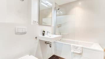 A modern bathroom with a white sink, mirror, and bathtub.