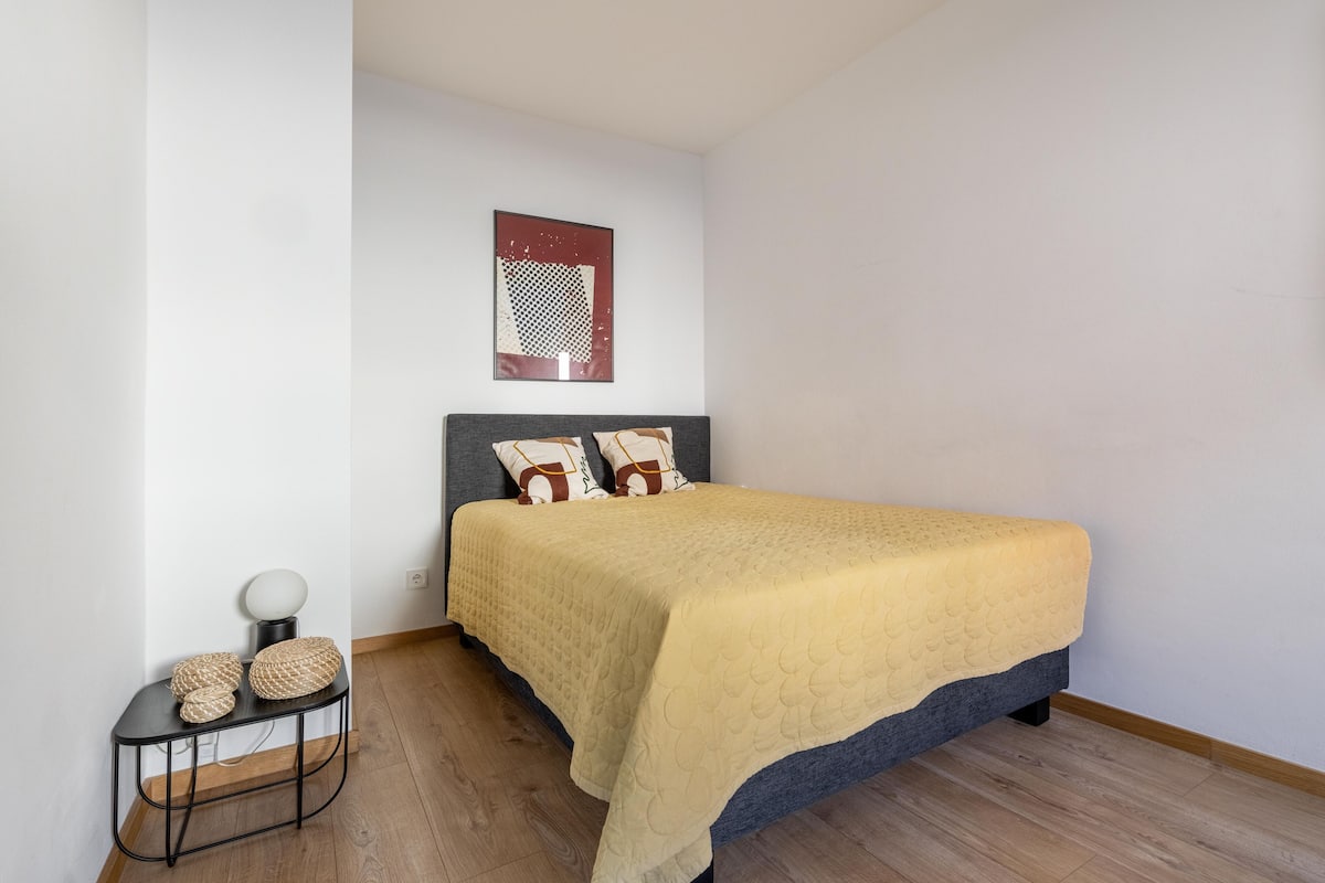 A bedroom with a bed, a bedside table, and a wall-mounted artwork.