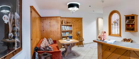 Una zona de estar acogedora con un sofá, estanterías de madera, una mesa y un espejo decorativo.