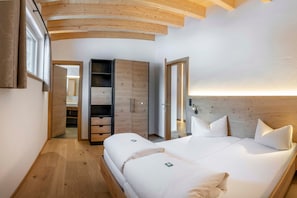 A bedroom with a wooden ceiling, a bed with white bedding, a wardrobe, and a mirror.