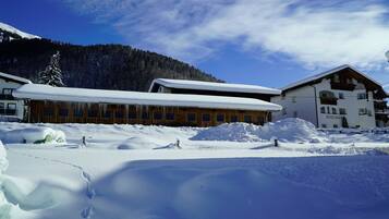Ein schneebedecktes Gebäude mit Holzfassade, einem Berg im Hintergrund und wolkenlosem Himmel.