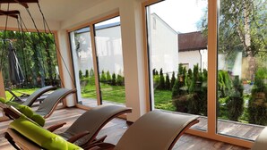 A room with large windows, a wooden floor, and two lounge chairs with green cushions. - Vacation apartment Vergissmeinnicht - ROSENHOF Apartments & Wellness & Bauernhof (Nauders)