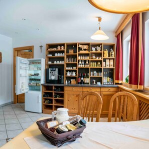 Una cocina con armarios de madera, un refrigerador y un comedor con una mesa preparada para dos.