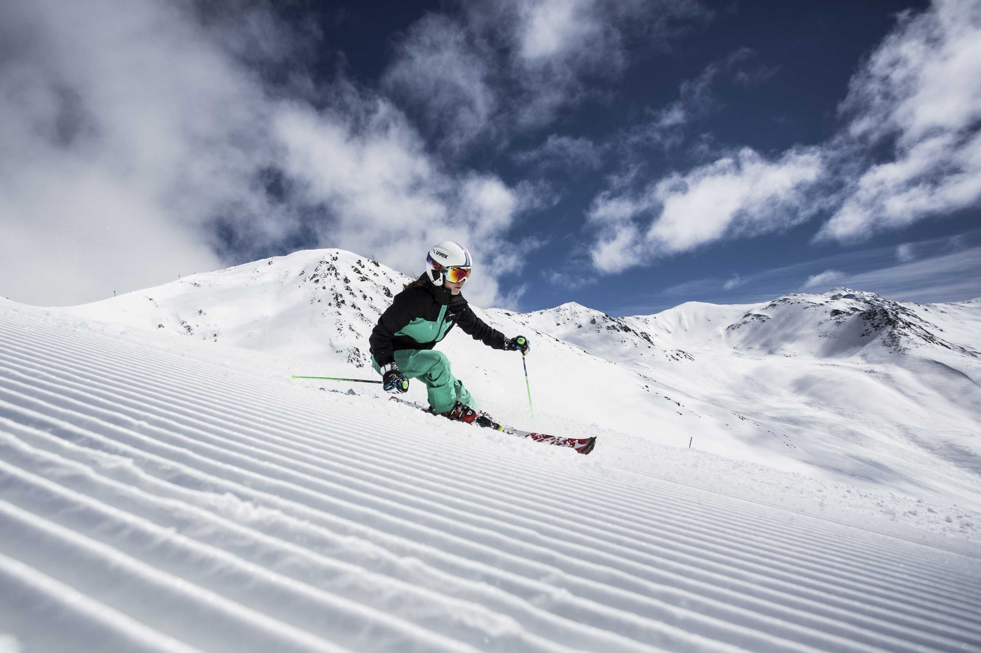 A skier on a snowy slope with mountains in the background.