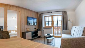 Un salon moderne avec un mur en bois, un téléviseur à écran plat, un canapé, une table à manger et une petite table d’appoint.
