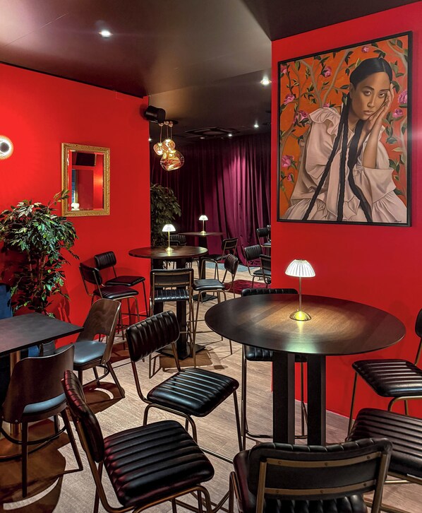 A restaurant with red walls, multiple tables and chairs, and a large painting on the wall. - Marmont Hotel (Geneva)