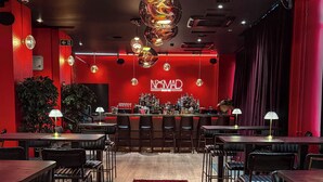 Interior de restaurante con alfombra roja, zona de bar e iluminación moderna.