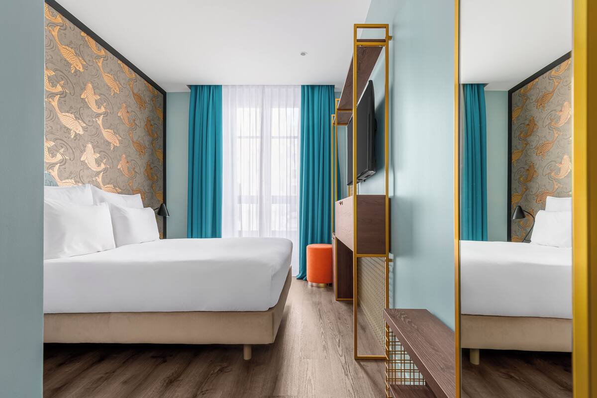 Una habitación de hotel con dos camas, televisión y suelo de madera.