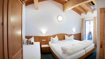 Ein Schlafzimmer mit Holzbettrahmen, zwei Betten, einem Nachttisch und einem Teddybären.