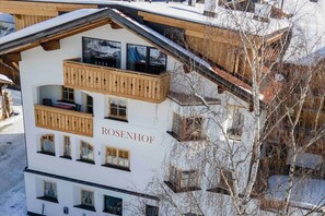 A multi-story hotel with balconies, a ski slope in the background, and the name 'ROSENHOF' on the facade.
