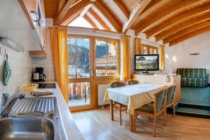 Una cocina con lavamanos, estufa y ventana con vistas a la montaña.