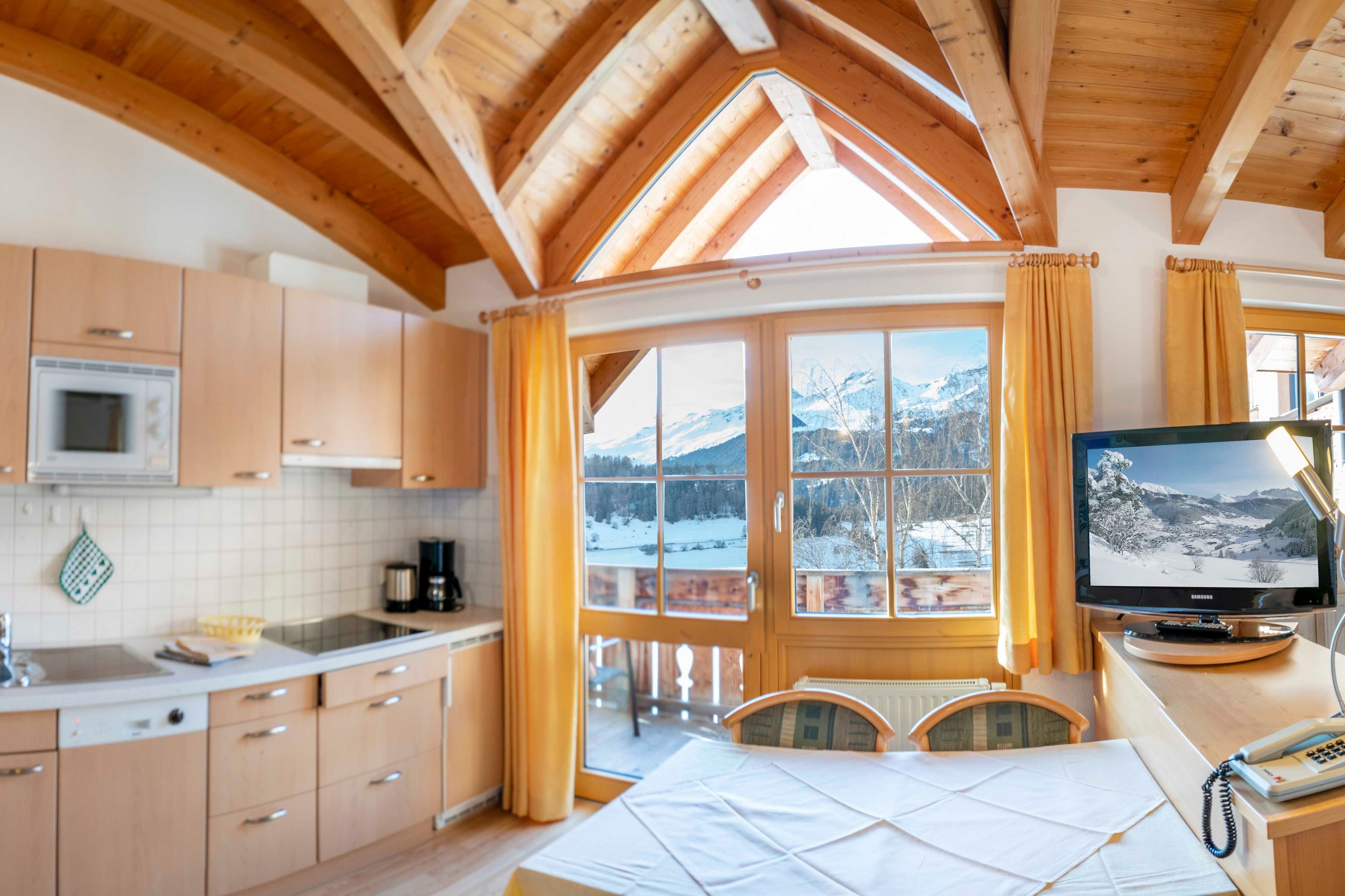 A kitchen with wooden cabinets, a microwave, and a window with curtains.