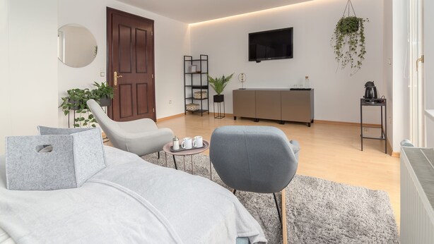 A modern living room with a sofa, armchair, and a coffee table. - Rooms and Apartments in Eagle's Nest (Ljubljana)