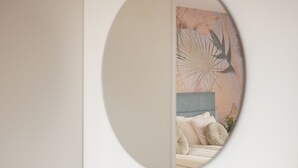 A round mirror on a wall with a bed and a plant in the foreground. - Rooms and Apartments in Eagle's Nest (Ljubljana)
