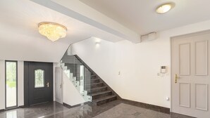 A spacious interior with a marble floor, a staircase with glass railings, and a chandelier. - Rooms and Apartments in Eagle's Nest (Ljubljana)