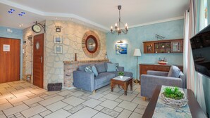 A living room with a stone wall, a fireplace, a sofa, a coffee table, and a wooden cabinet. - Apartamenty Sun & Snow Willa Jazgór (Wladyslawowo)