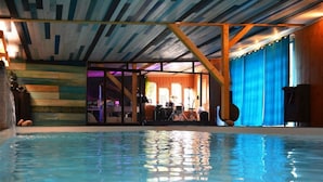 Une piscine intérieure donnant sur une pièce où se trouvent des instruments de musique et une scène.