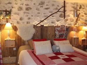 A cozy bedroom with a rustic wooden headboard, a quilted bedspread, and two bedside lamps.