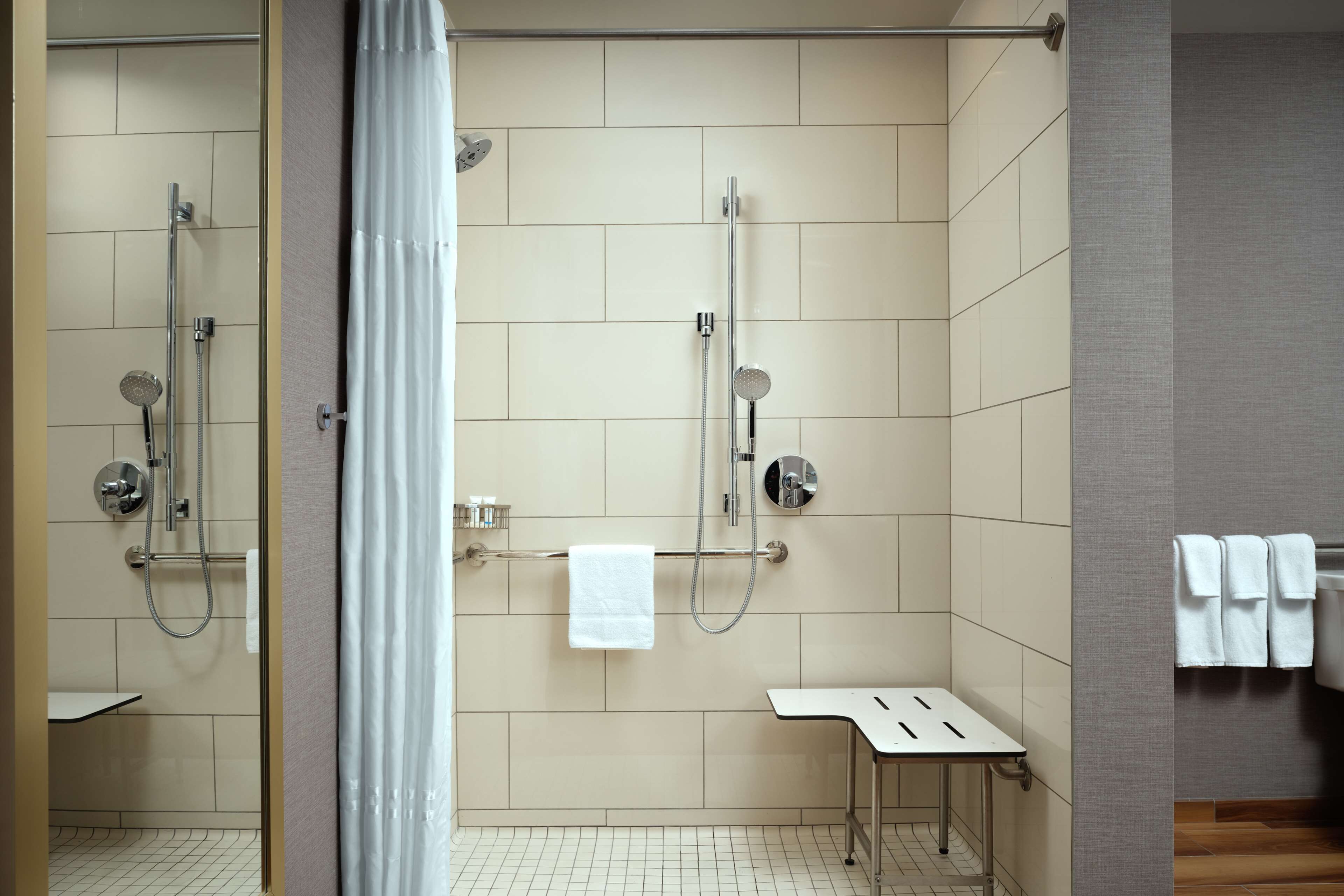 Un baño moderno con ducha, una mesita pequeña y un perchero para toallas.