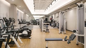 A gym with exercise equipment, a bench, and a mirrored wall.