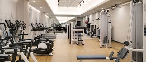 A gym with exercise equipment, a bench, and a mirrored wall.