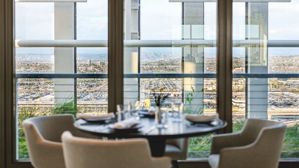 Ein Essbereich mit einem Tisch für vier Personen, große Fenster mit Blick auf die Stadt.