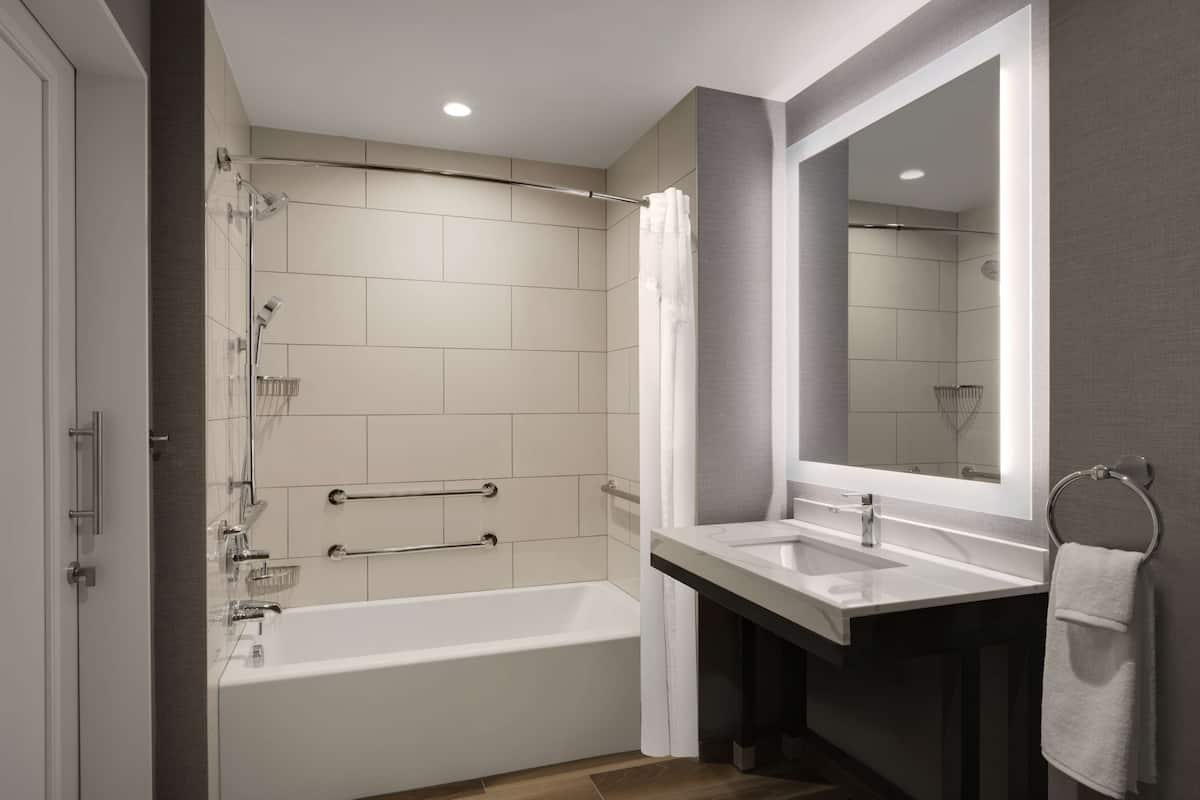 A modern bathroom with a bathtub, a large mirror, and a sink.