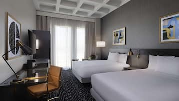 Een hotelkamer met twee bedden, een bureau met stoel, een televisie en kunstwerken aan de muren.