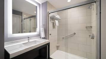 A modern bathroom with a large mirror, two sinks, a shower, and a bathtub.