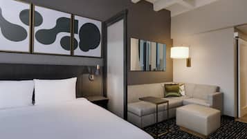A hotel room with a large bed, a sofa, a small table, and a lamp.