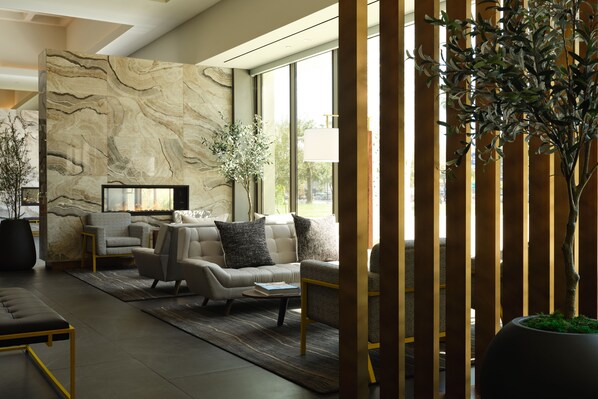 A modern living room with a marble wall, a sofa set, a coffee table, and a potted plant. - Hyatt House LAX/Century Blvd (Los Angeles)