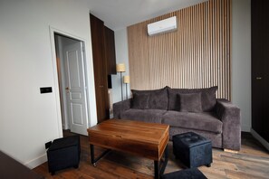 A modern living room with a wooden coffee table, a dark sofa, and a black ottoman.
