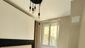 Une chambre d’hôtel avec un grand lit, une table de chevet, une fenêtre donnant sur l’extérieur et un luminaire au plafond.