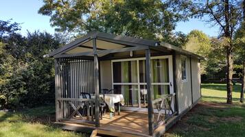 A small, single-story wooden structure with a porch, a table, and chairs.