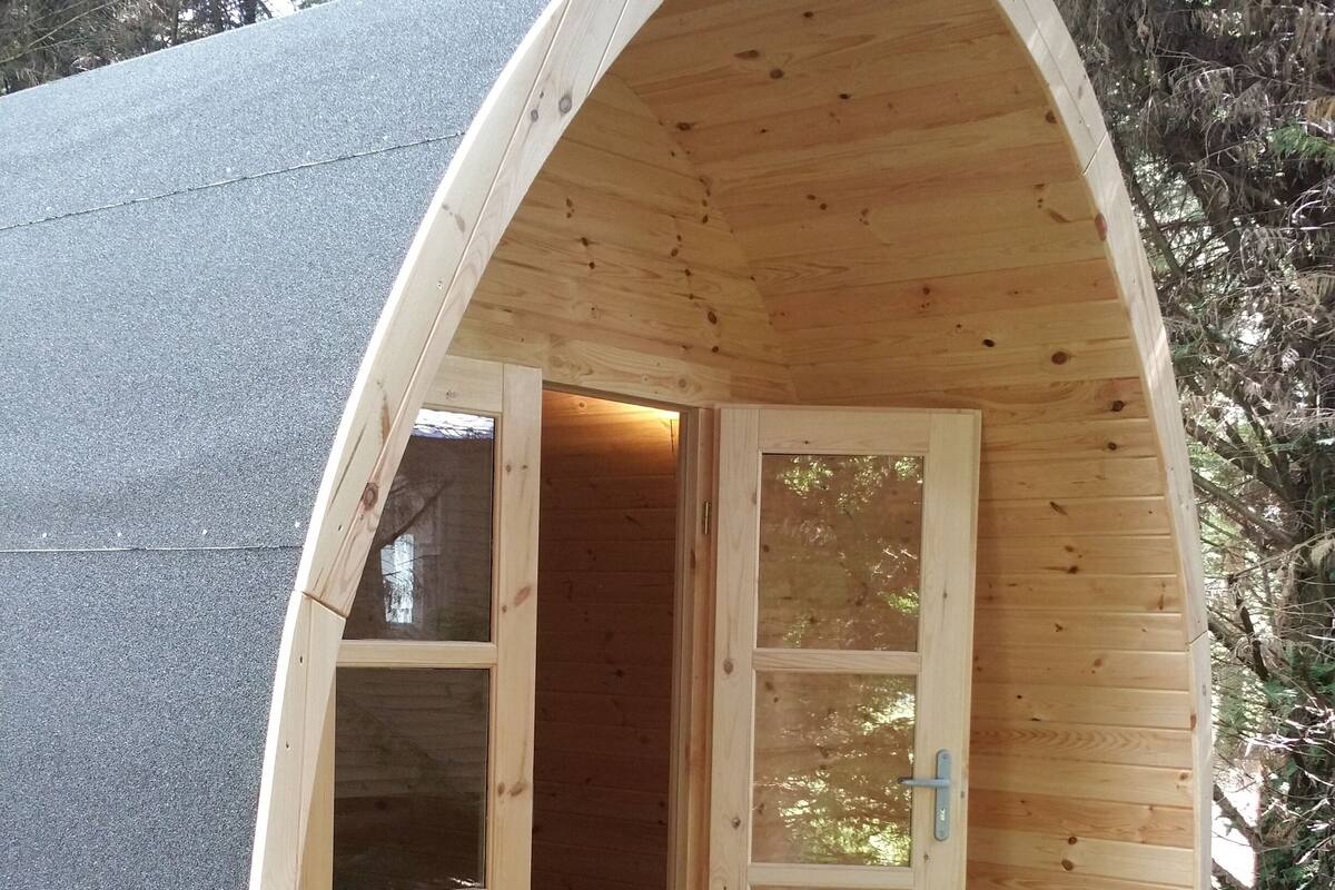 Een houten hutje met een schuin dak, twee grote ramen en een deur.