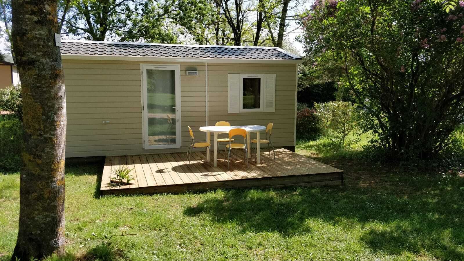Eine kleine, eingeschossige Holzhütte mit einer Terrasse, einer Schiebetür und einem Fenster.